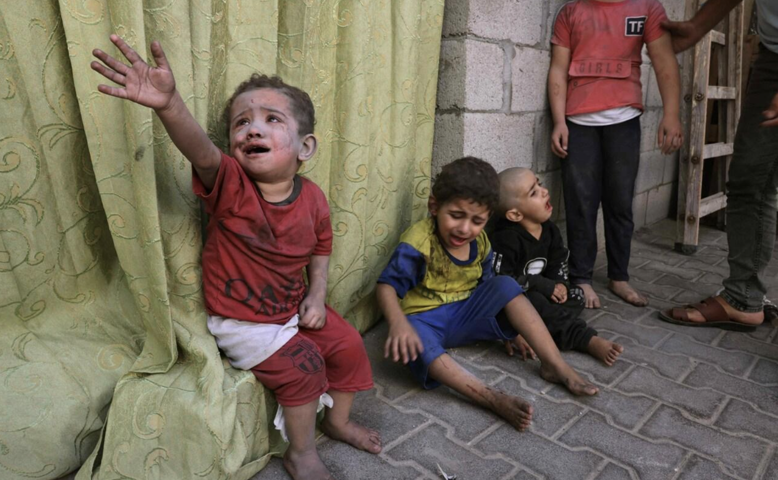 Palestinian children covered in dust from an Israeli air strike sit in the grounds of a hospital in Rafah CREDIT: MOHAMMED ABED/AFP via Getty Images